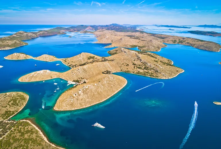 Aerial of a sheltered Kornati archipelago anchorage bay with white boats, Croatia