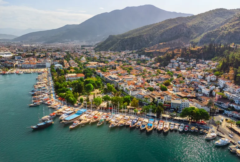 Aerial of Fethiye waterfront with gulets lined along quay beneath mountains