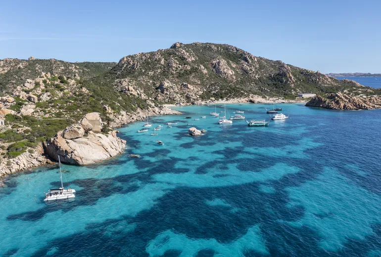 Aerial of granite cove anchorage with catamaran and yachts, La Maddalena archipelago