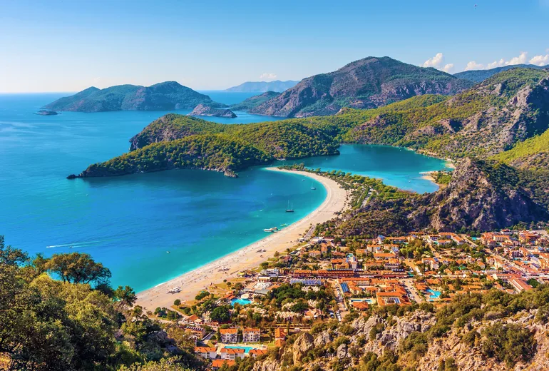 Aerial of Ölüdeniz lagoon, sand spit, beach resort and mountain ridges, Türkiye