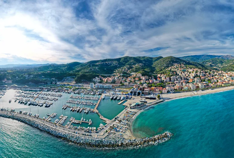 Aerial panorama of an Italian Riviera marina town with breakwaters and moored yachts