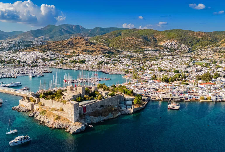 Aerial panorama of Bodrum castle, marina masts, whitewashed town and hills, Turkiye