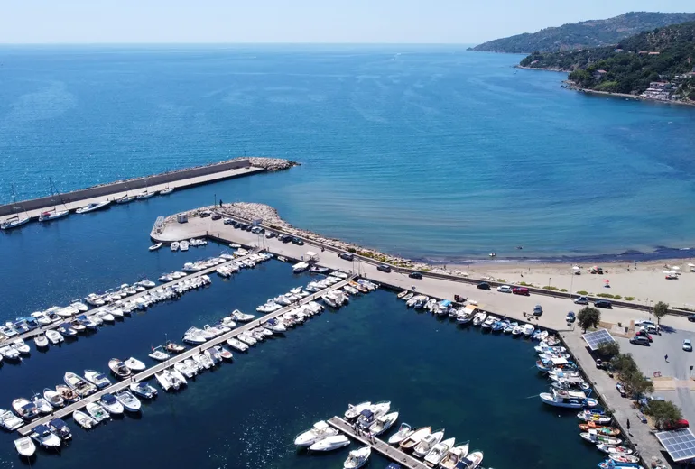 Aerial view of Casalvelino marina breakwater, moored small boats and adjacent sandy beach