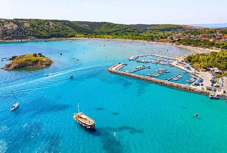 Busy turquoise bay with a marina and beach on the Croatian coast