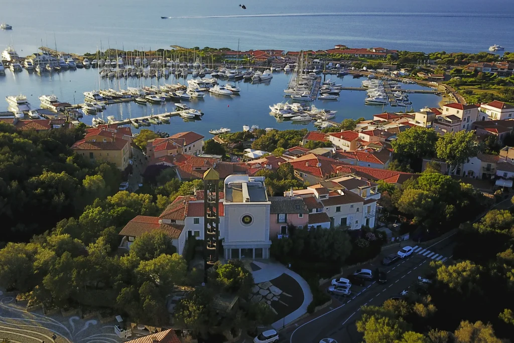 Aerial of Porto Rotondo village, church tower and marina at golden evening light