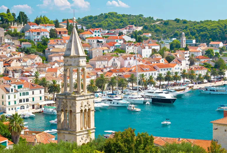 Hvar town bell tower, palm-lined waterfront and yacht-filled harbour viewed from above, Croatia