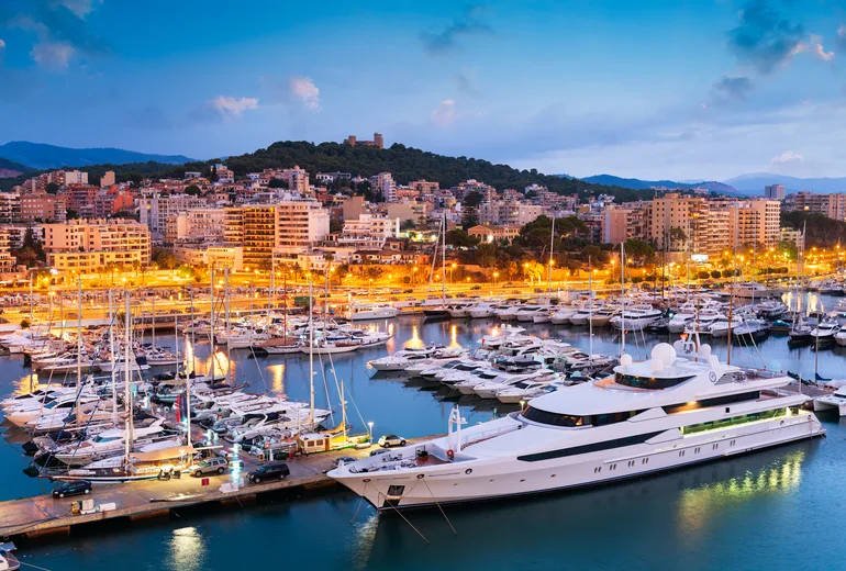 Palma marina at dusk with a superyacht, sailboats and the illuminated city, Mallorca