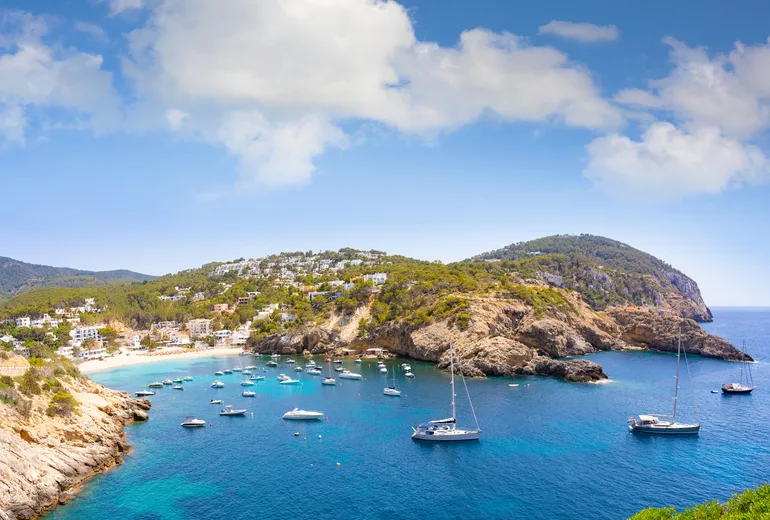 Sailboats anchored in Cala d'Hort cove below the village, Ibiza, Spain