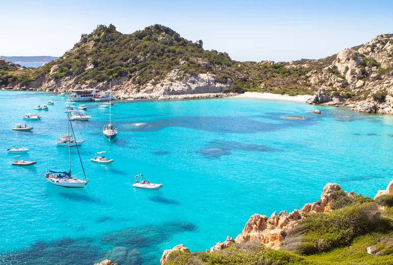 Sailboats anchored in shallow turquoise bay, La Maddalena archipelago, Sardinia