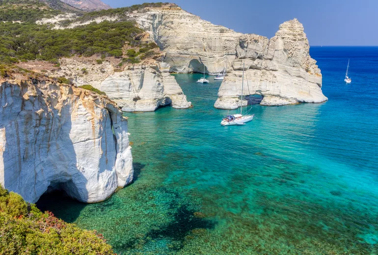 Sailing yachts anchored beneath the white sculpted cliffs of Kleftiko, Milos, Greece