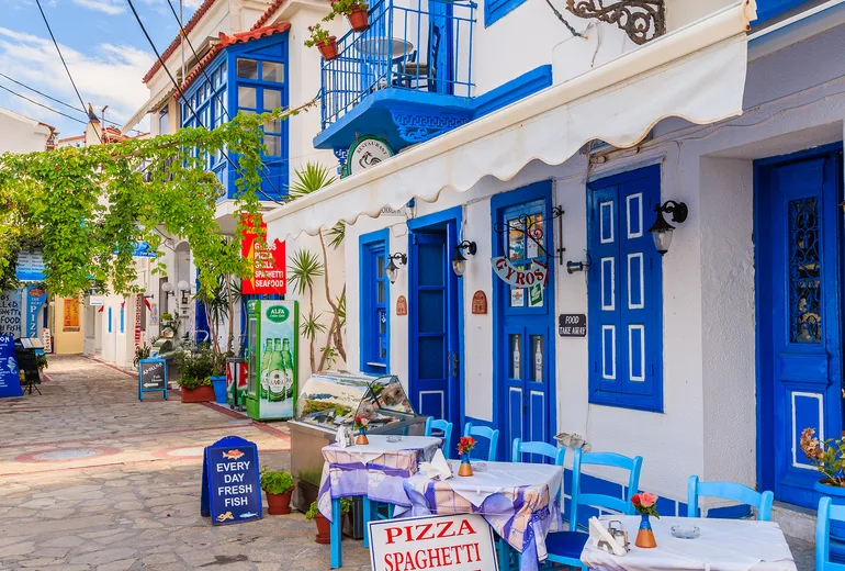 Taverna tables and menu boards in a blue-and-white Greek island street