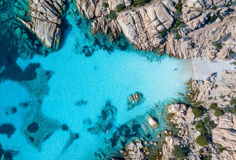 Top-down aerial of turquoise cove between granite rocks on Caprera, Sardinia