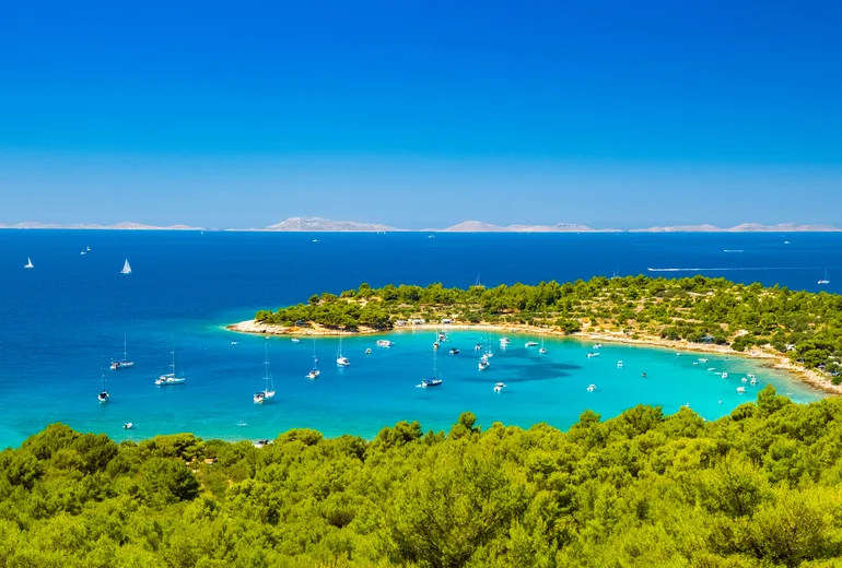 Turquoise bay anchorage with yachts, pine shores and distant islands, Croatia